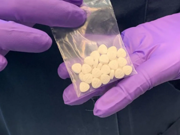 Manos enguantadas afirmando una bolsa de nitazenos