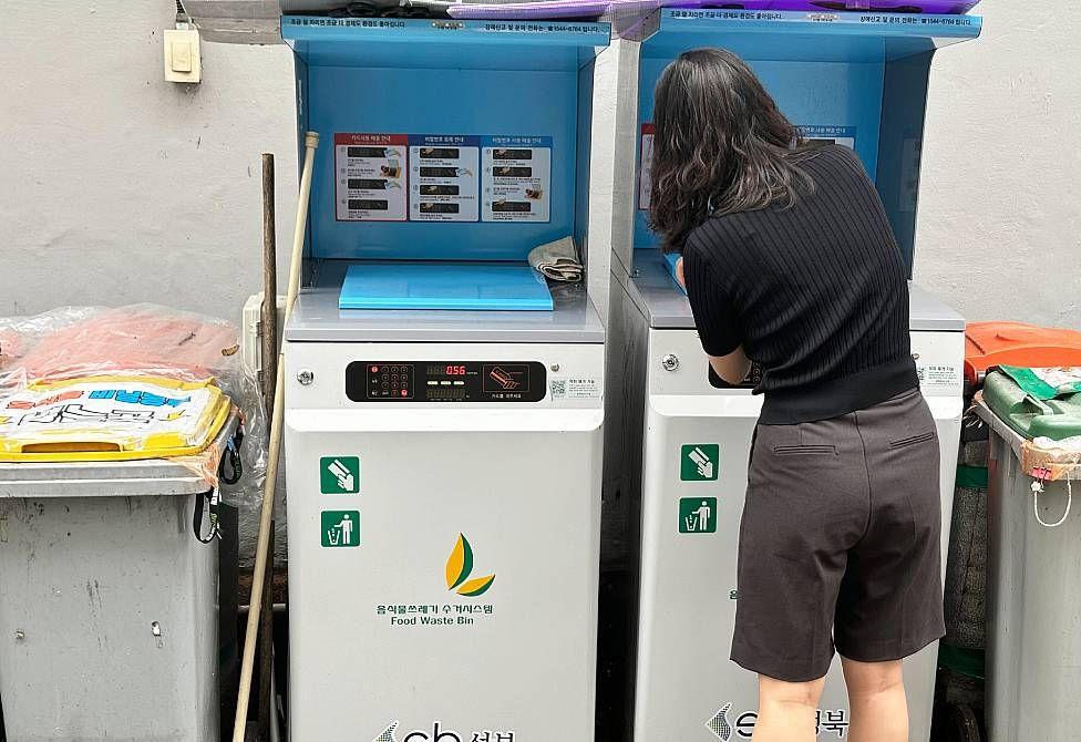 Yuna tirando residuos de comida en una máquina