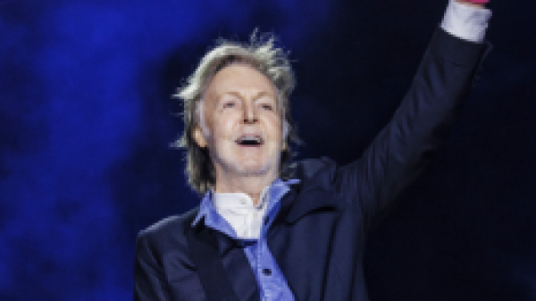 Paul McCartney con una guitarra elevando el puño de su mano