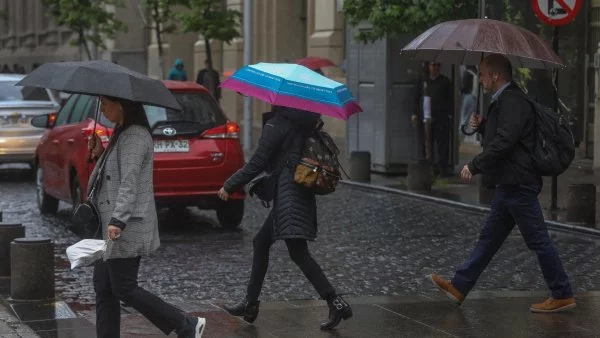 Personas caminando con paraguas en Santiago