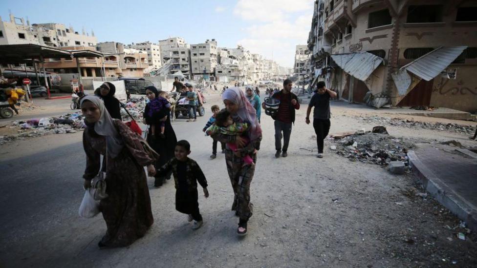 Un grupo de palestinos desplazándose entre escombros.