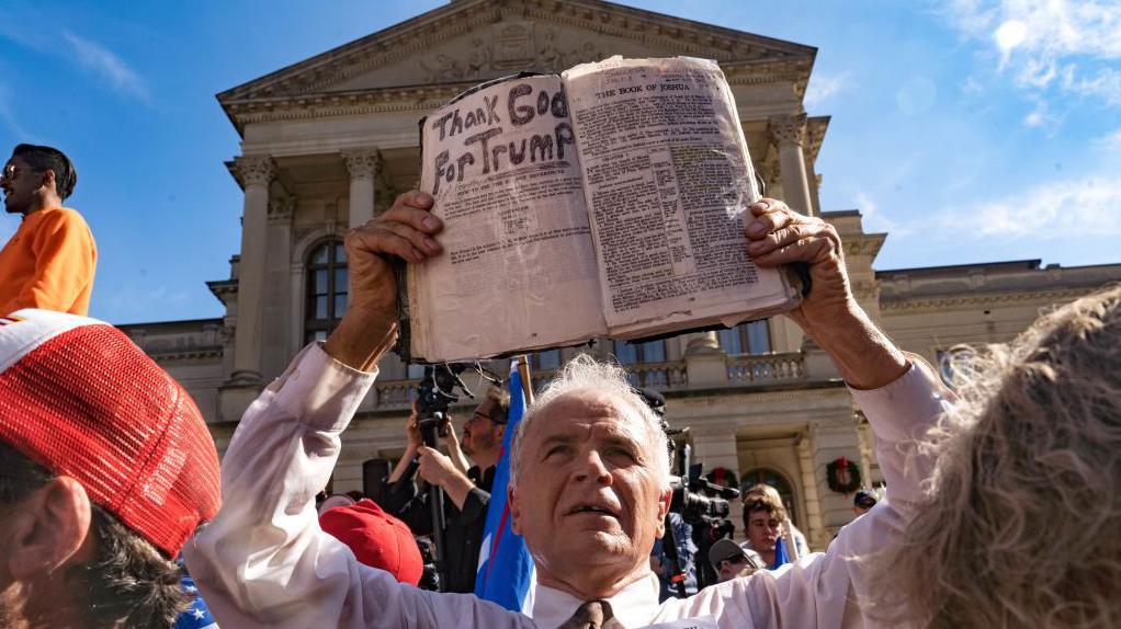 Un manifestante sostiene una Biblia que dice "Gracias a Dios por Trump" frente al Capitolio del estado de Georgia en noviembre de 2020.