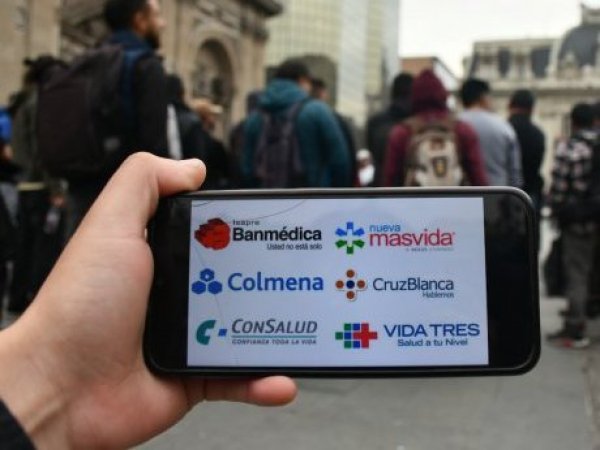 Persona con teléfono mostrando el logo de las Isapres