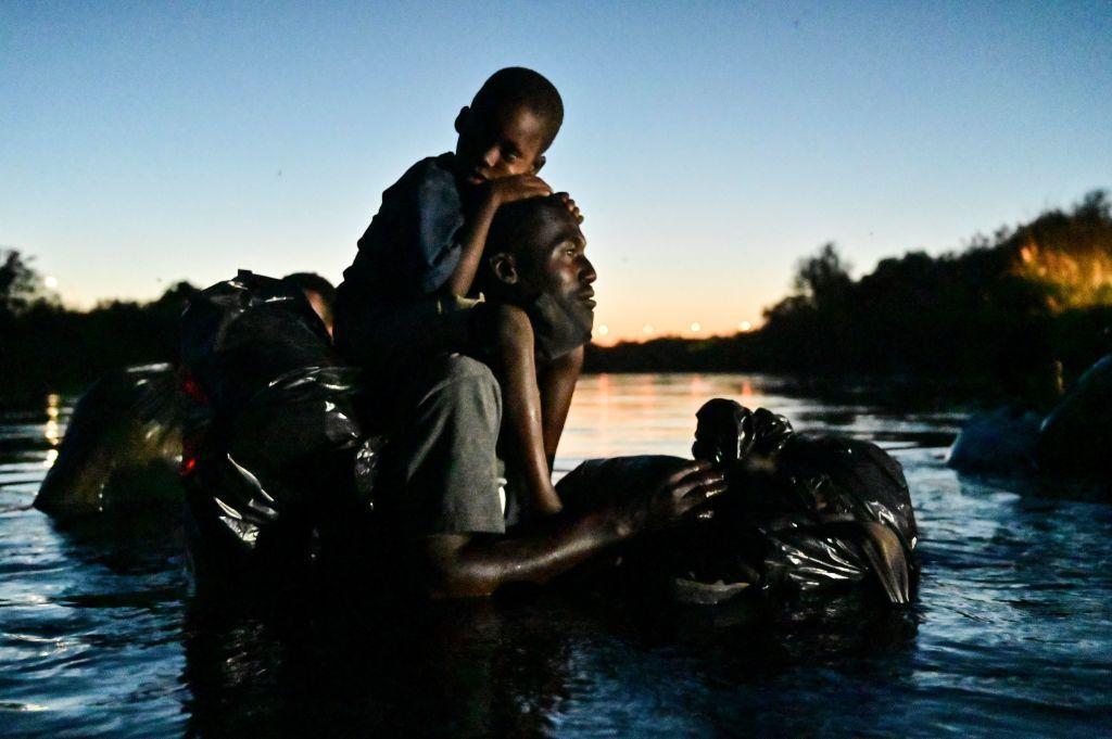 Migrante en el río con su hijo en brazos.
