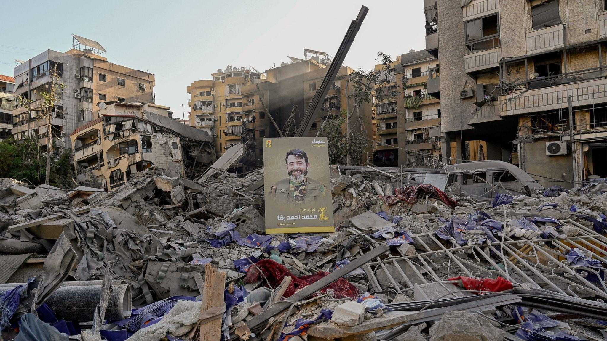 Una imagen de un combatiente de Hezbolá se muestra sobre los escombros tras un ataque israelí al suburbio.