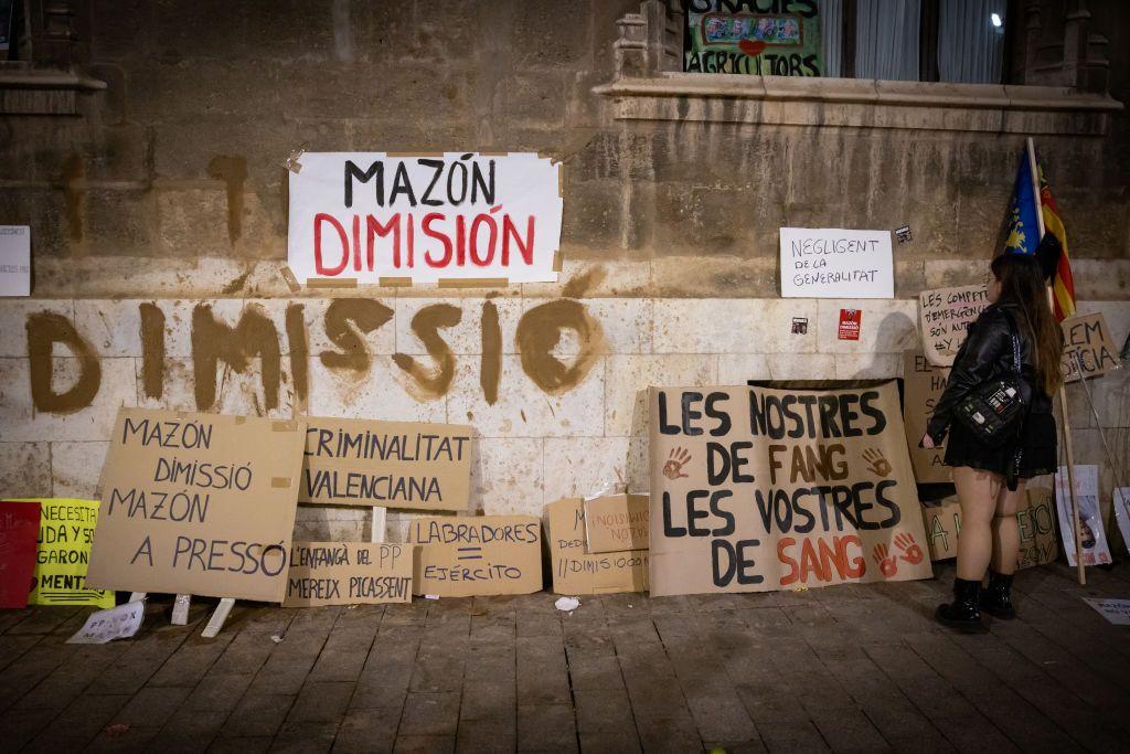 algunas pancartas con diversos mensajes en contra del gobierno. Una de ellas lee "mazón dimisión".