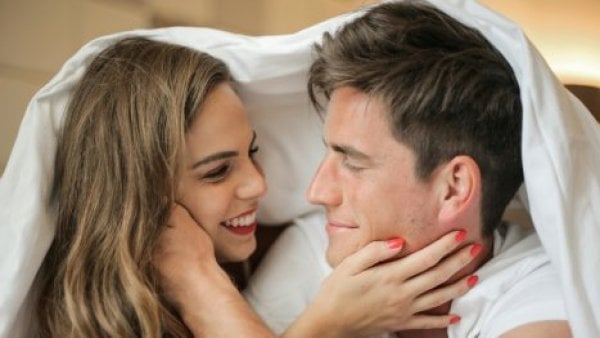 Pareja conversando bajo las sábanas