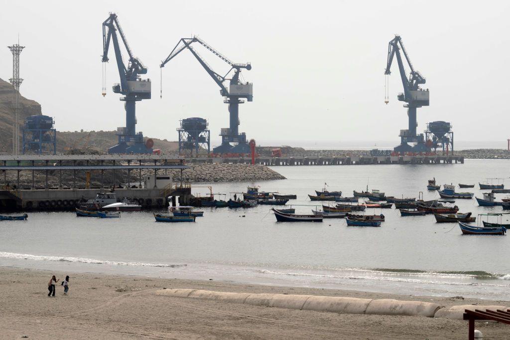 Pequeños barcos pesqueros amarrados en la playa Chancay, con el gran puerto en construcción de fondo.