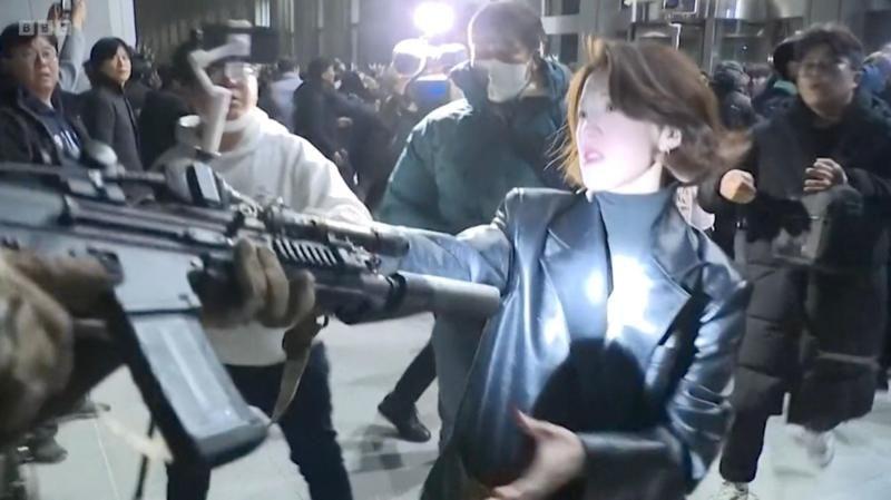 Una mujer agarra el fusil de un soldado en los aledaños del Parlamento surcoreano.