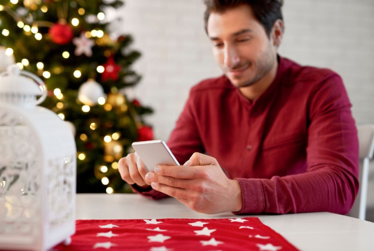 Persona enviando un WhatsApp con árbol navideño de fondo