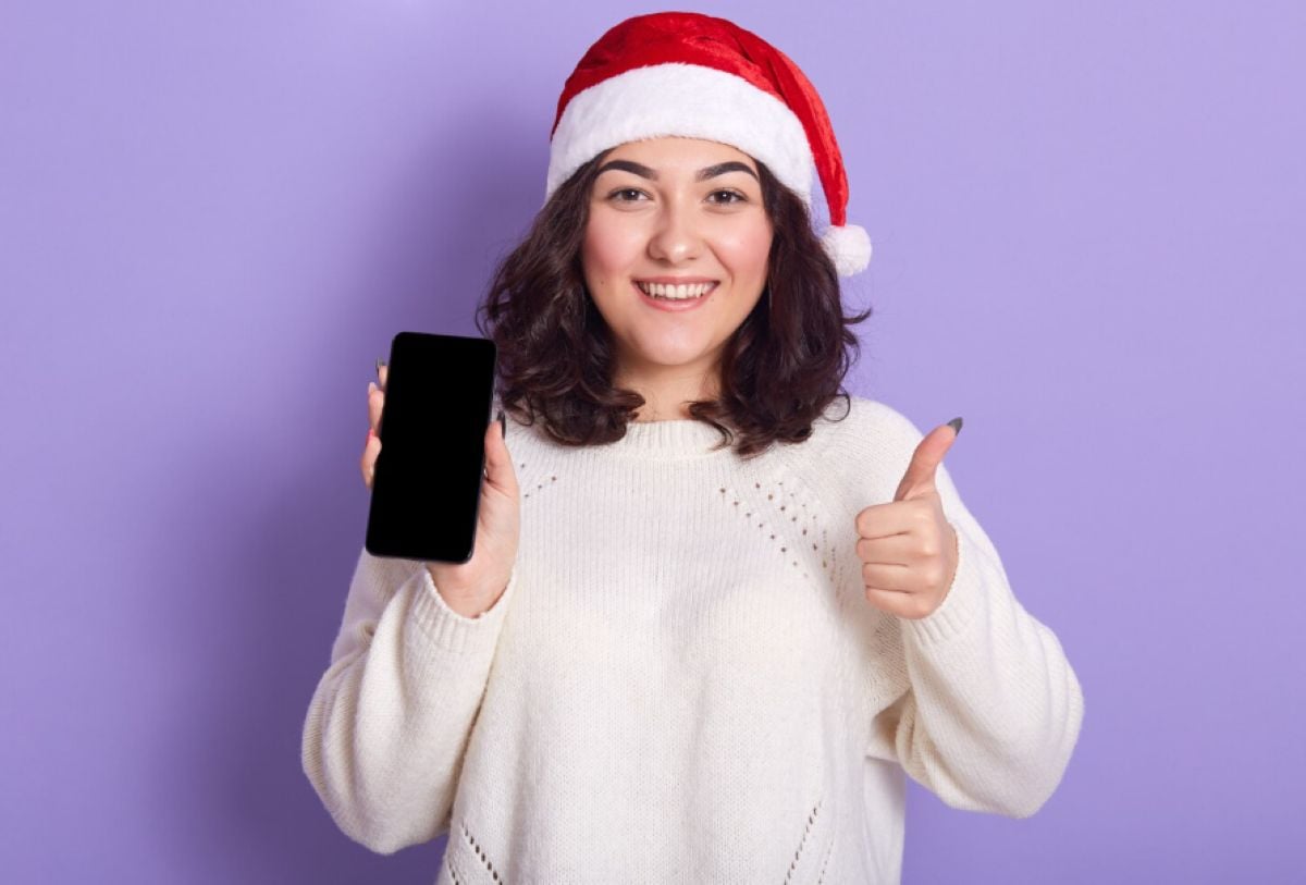 Mujer con gorro de Navidad sujetando un teléfono