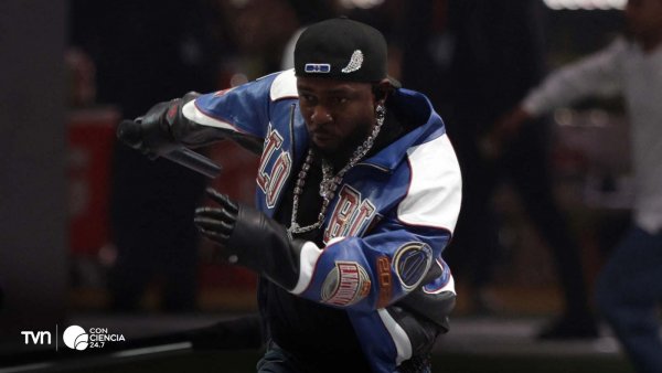 Imagen de Kendrick Lamar en un concierto, con un fondo vibrante y luces rojas.