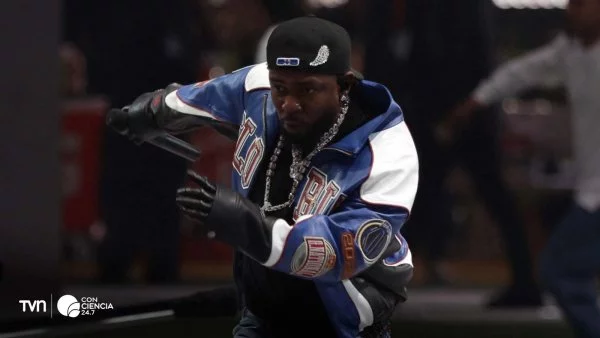 Imagen de Kendrick Lamar en un concierto, con un fondo vibrante y luces rojas.