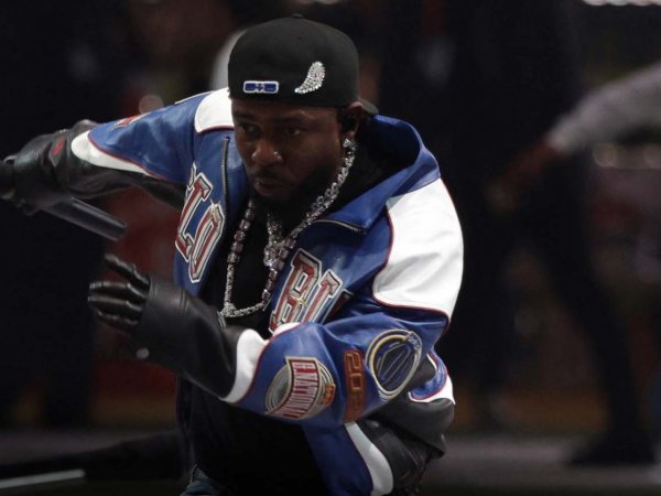 Imagen de Kendrick Lamar en un concierto, con un fondo vibrante y luces rojas.