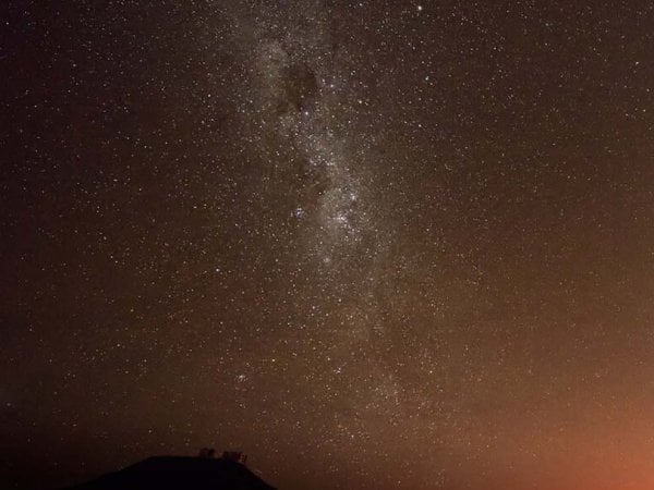 Cielo nocturno en el norte de Chile con telescopios en primer plano bajo estrellas brillantes.