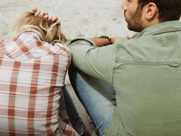 Pareja sentada en silencio en un parque, reflejando distancia emocional.