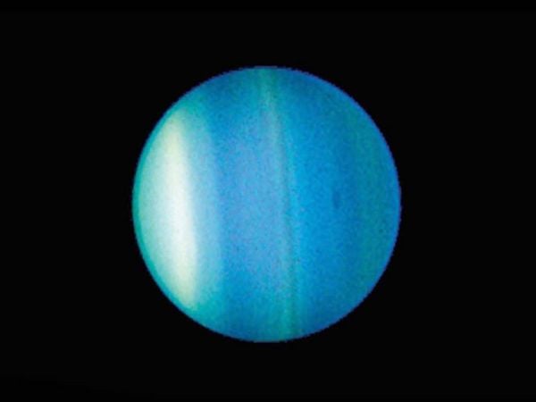 Imagen de Urano captada por el telescopio espacial Hubble, con sus auroras visibles cerca de los polos.