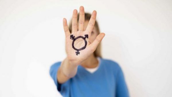 Persona con la mano pintada con la señal de una persona transexual