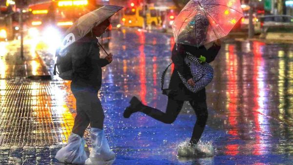 Persona corriendo en la lluvia con paraguas.
