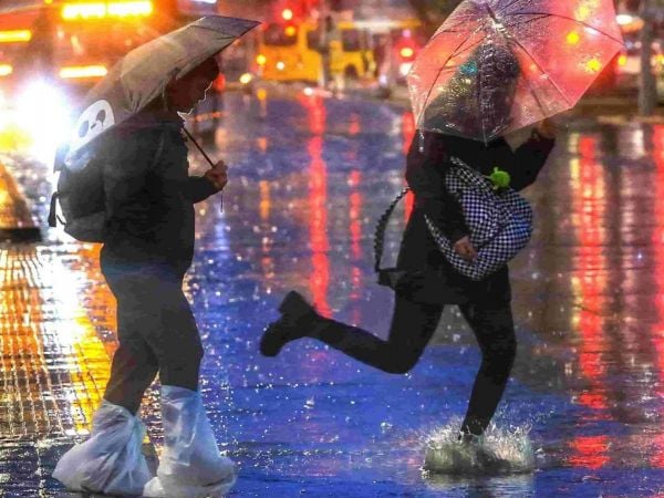 Persona corriendo en la lluvia con paraguas.