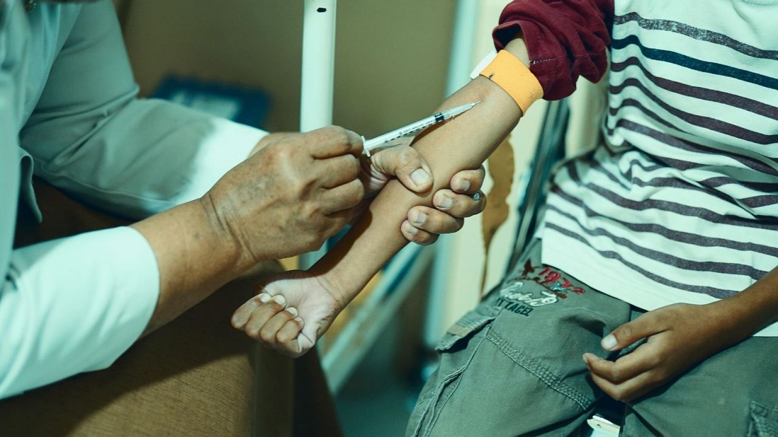 Persona vacunando en el brazo a un niño