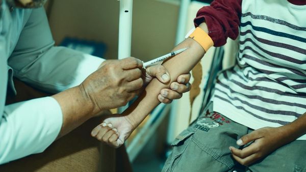 Persona vacunando en el brazo a un niño