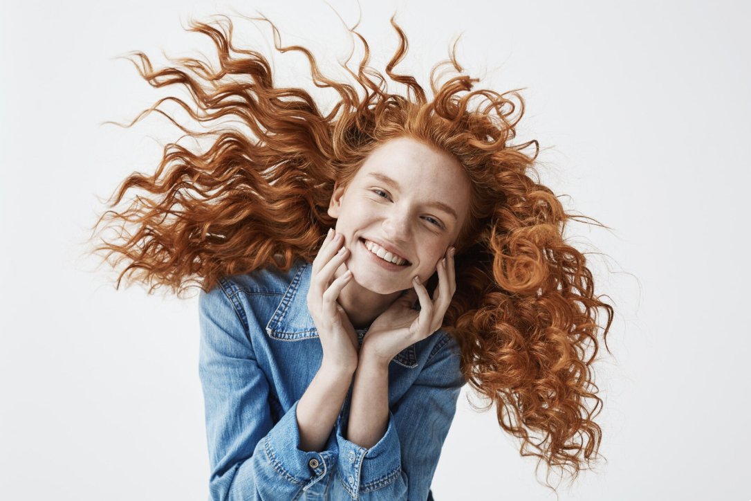 Mujer luce cabello pelirrojo rizado y sano