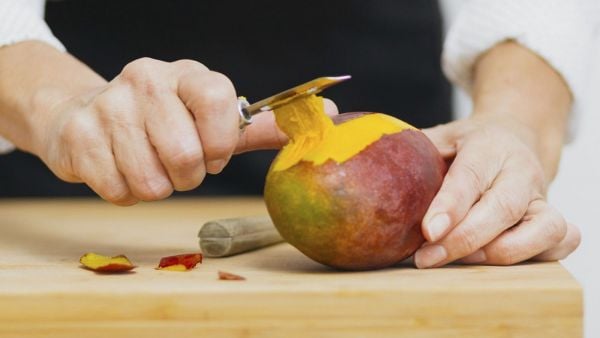 Persona cortando un mango.
