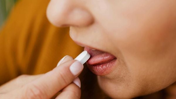 Mujer tomando pastilla. Referencial.