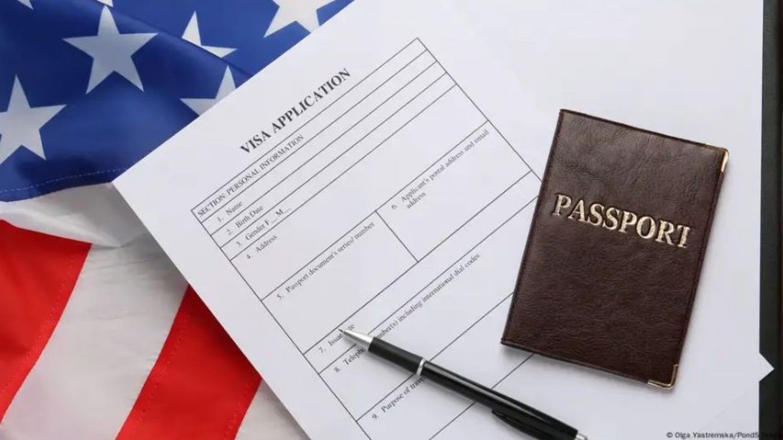 Bandera de EE.UU. y documento de visa junto a un lápiz.