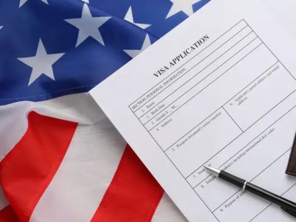 Bandera de EE.UU. y documento de visa junto a un lápiz.