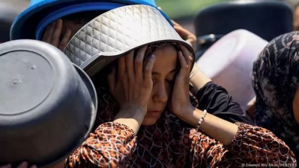 Mujer con un recipiente en la cabeza y sus manos en la cara en modo de desesperación.