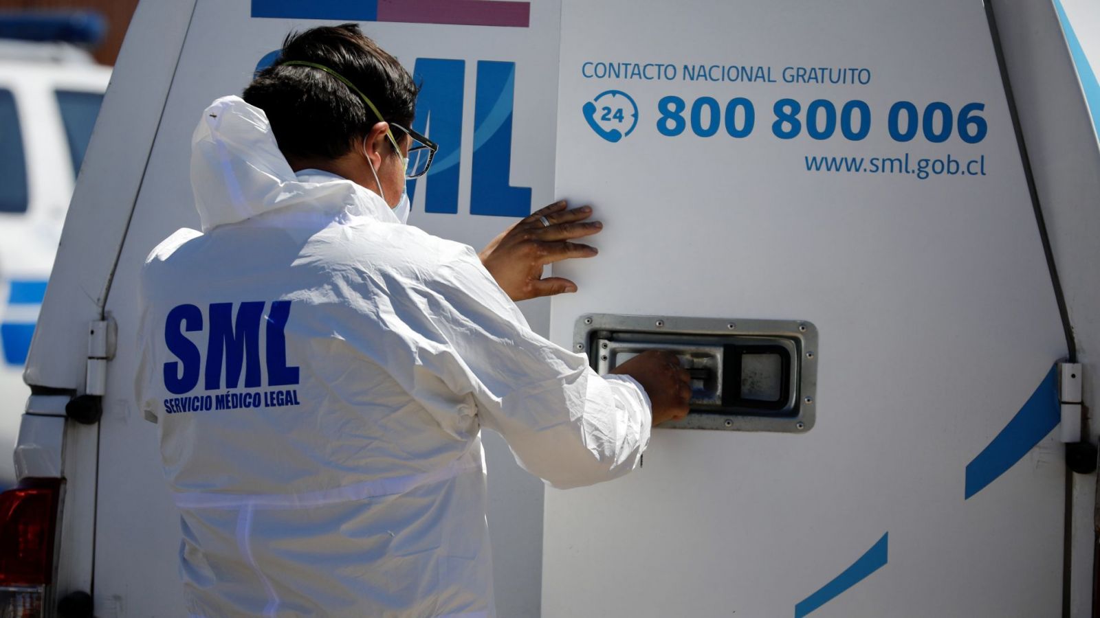 Funcionario Servicio Médico Legal cerrando la puerta de una camioneta blanca con el logo SML