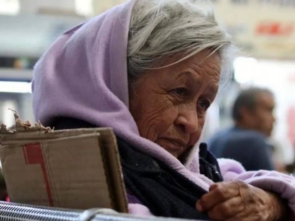 Adulta mayor envuelta en un polerón morado, sosteniendo un cartón