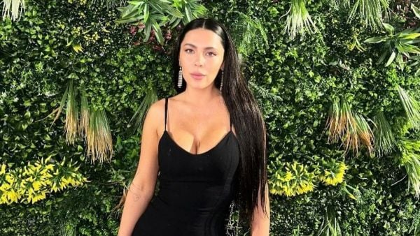 Daniela Aránguiz con un vestido negro sin mangas, posando frente a un fondo verde de plantas