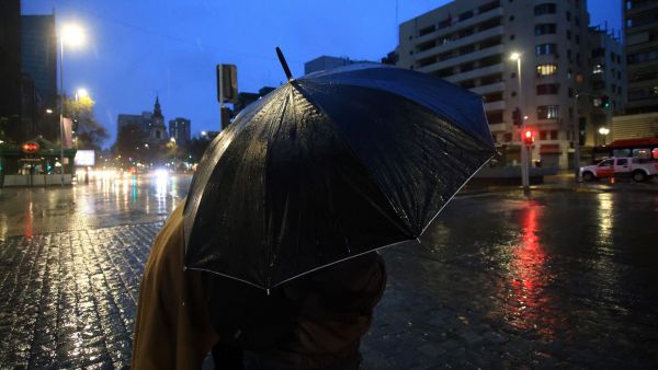 Persona con paraguas de color morado bajo la lluvia.