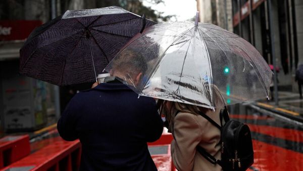 Personas bajo la lluvia con paraguas.