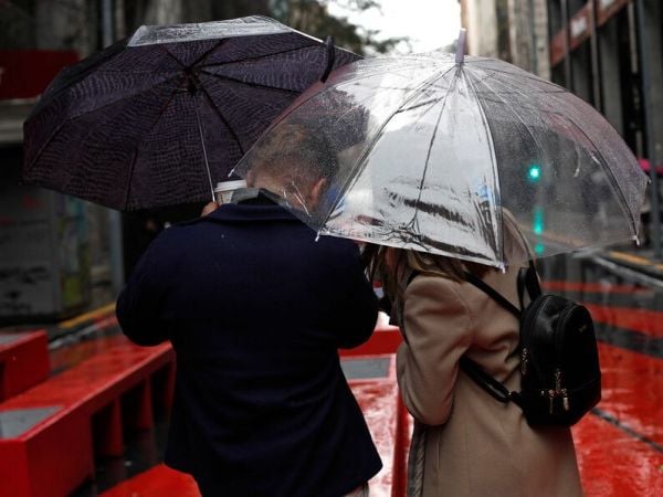 Personas bajo la lluvia con paraguas.