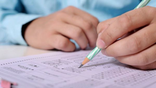 Primer plano de las manos de una persona rellenando una hoja de respuestas