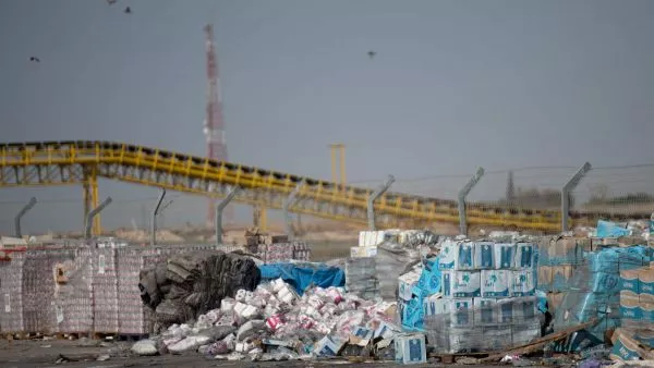 Vista de cajas de ayuda humanitaria que se descomponen bajo el sol. Aves de rapiña sobrevuelan las cajas