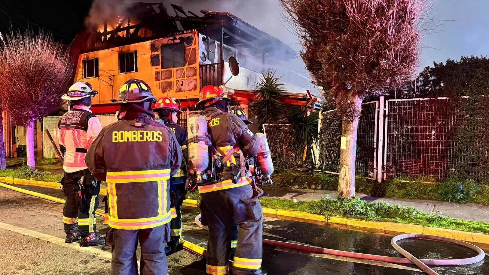 Bomberos en casa consumida por las llamas.