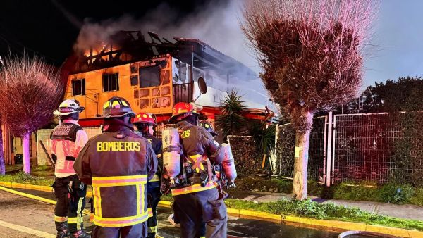 Bomberos en casa consumida por las llamas.