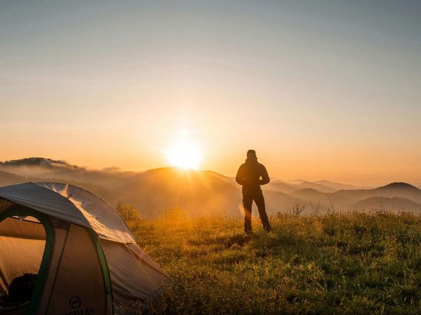 Persona caminando en un parque urbano, rodeada de árboles y naturaleza.