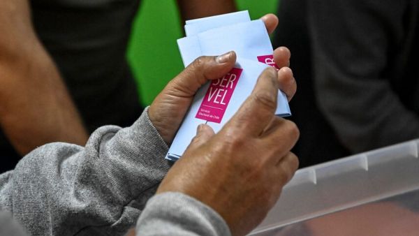 Persona sujetando votos electorales del Servel en sus manos