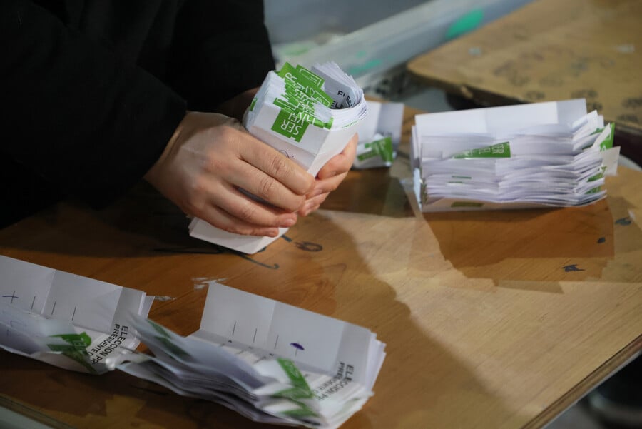 Manos sujetando votos del Servel en elecciones
