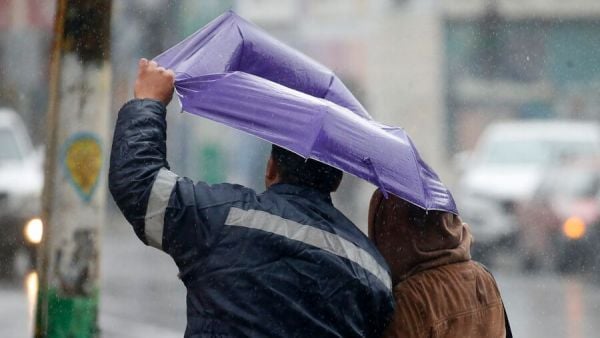 Personas con paraguas bajo la lluvia con viento.