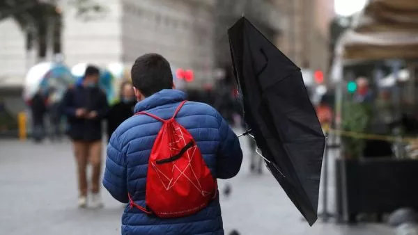 Persona caminado con paraguas y viento