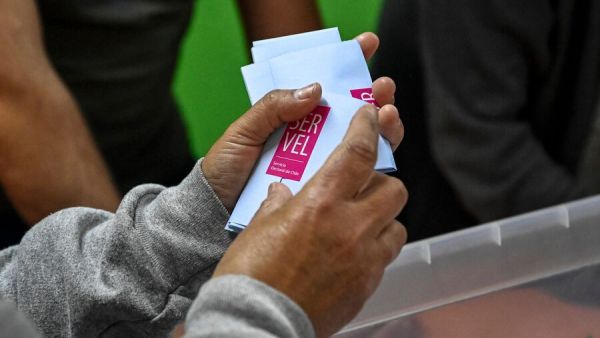 Mano sujetando voto con sticker del Servel en elecciones