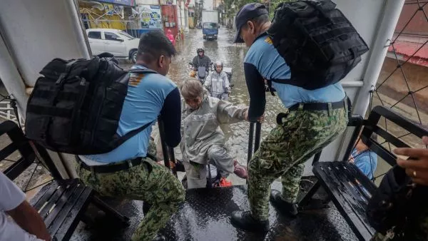 Dos personas con uniformes oficiales ayudan a damnificados en el paso del tifón en Filipinas.