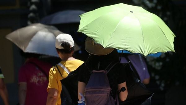Personas con sombrilla en el calor. Foto referencial del tiempo en Santiago en elecciones